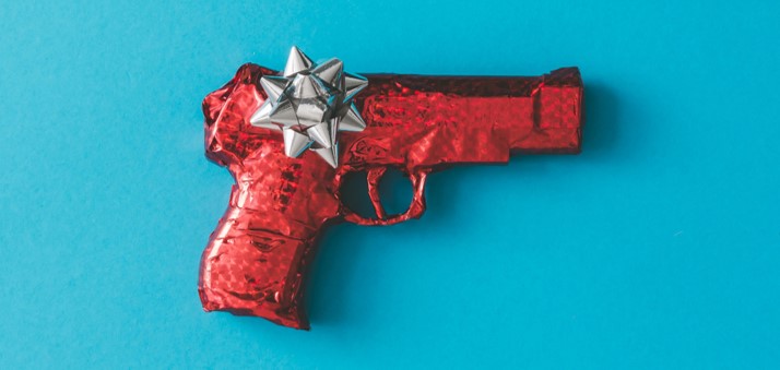Une arme est emballé dans du papier cadeau à paillette rouge sur fond bleu