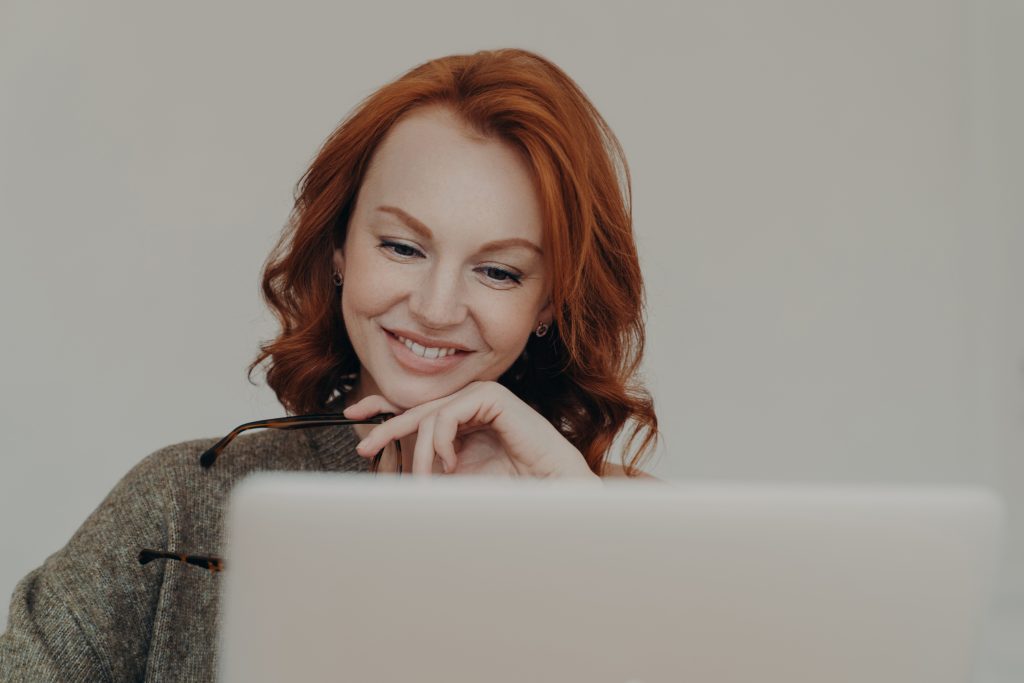 Femme rousse souriante communique avec un ordinateur - télétravail - manager à distance