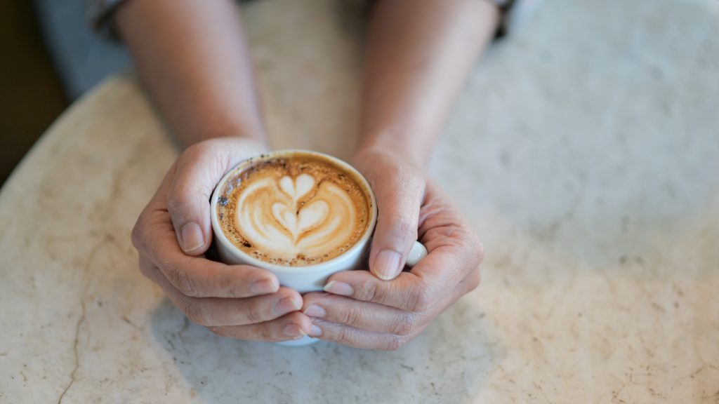 Latte café texture coeur à la main.